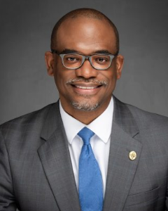 Man in grey suit smiling for a headshot
