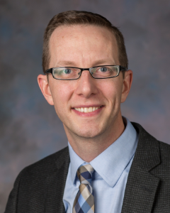 Man in grey suit smiling for a headshot
