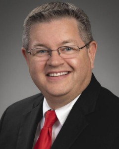 Man in black suit smiling for a headshot