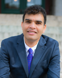 Man in navy suit smiling for a headshot